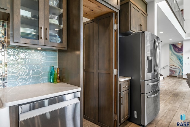 kitchen featuring stainless steel fridge with ice dispenser, dark brown cabinets, light hardwood / wood-style flooring, and tasteful backsplash