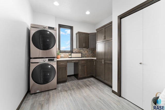 laundry area featuring cabinets, light hardwood / wood-style flooring, and stacked washer and dryer