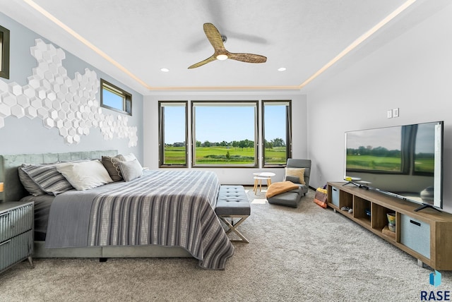 bedroom with radiator heating unit, ceiling fan, carpet, and a raised ceiling