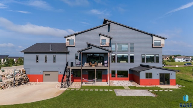 rear view of house featuring a deck, a patio, a lawn, and a garage