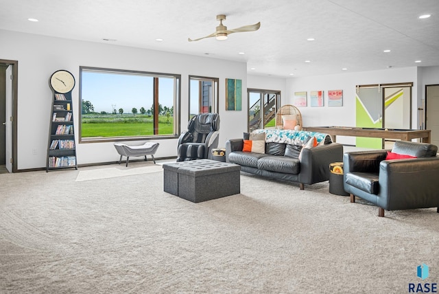 carpeted living room with ceiling fan and a barn door