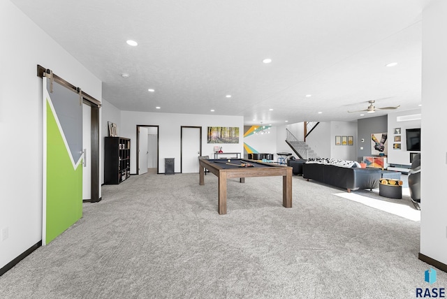 rec room with ceiling fan, a barn door, and light colored carpet