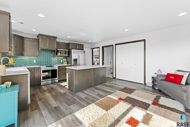 kitchen with appliances with stainless steel finishes, tasteful backsplash, sink, a kitchen island, and dark hardwood / wood-style floors