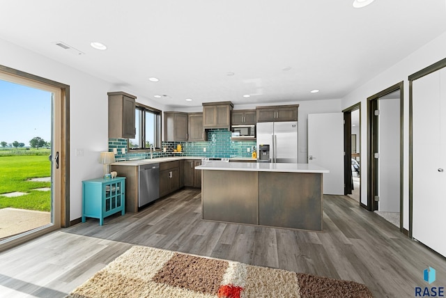 kitchen with a kitchen island, stainless steel appliances, tasteful backsplash, sink, and dark hardwood / wood-style floors