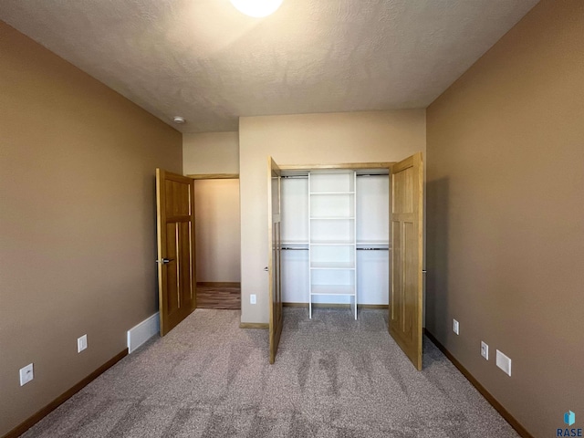 unfurnished bedroom with a closet, carpet flooring, and a textured ceiling