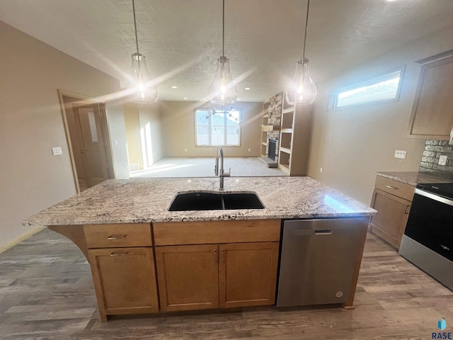 kitchen featuring sink, hanging light fixtures, appliances with stainless steel finishes, and light wood-type flooring