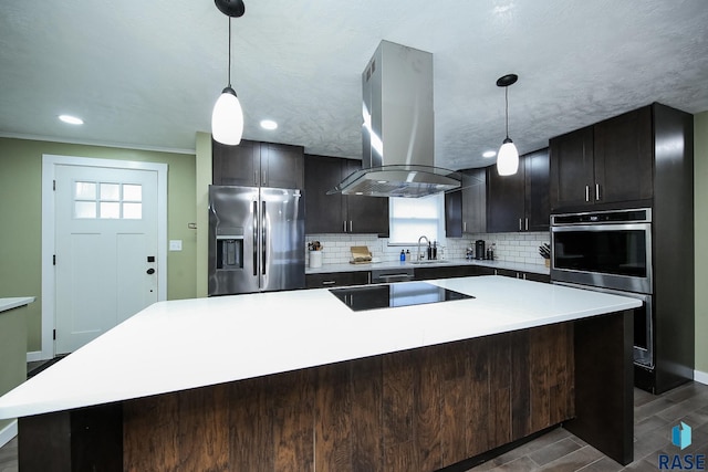 kitchen featuring pendant lighting, island range hood, a kitchen island, and appliances with stainless steel finishes