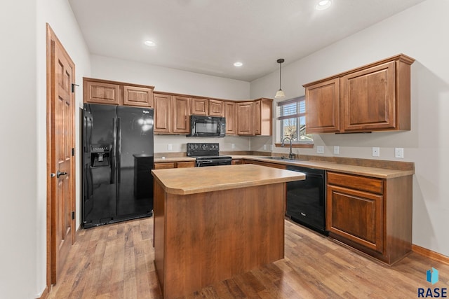 kitchen with sink, hanging light fixtures, a center island, light hardwood / wood-style floors, and black appliances