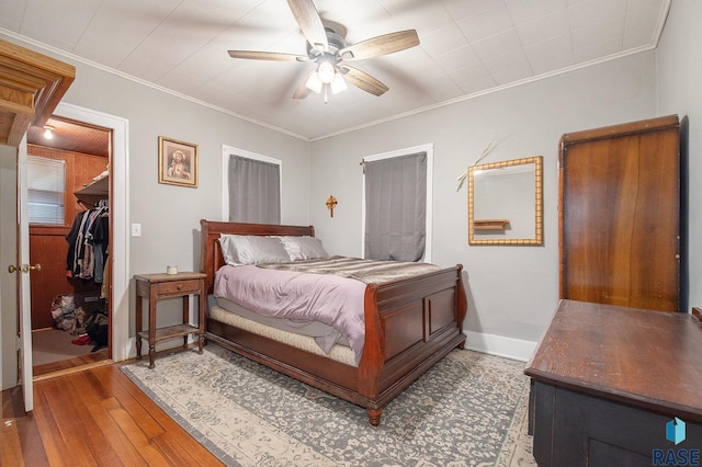 bedroom featuring hardwood / wood-style flooring, ornamental molding, ceiling fan, and a closet