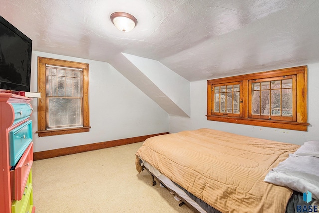 bedroom featuring lofted ceiling, carpet flooring, and a textured ceiling