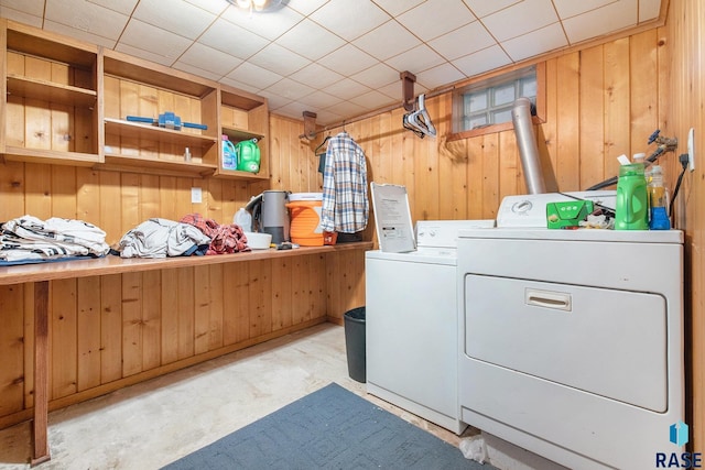 clothes washing area featuring wooden walls and washer and dryer