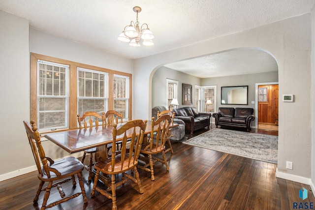 dining area with an inviting chandelier, dark hardwood / wood-style floors, and a textured ceiling