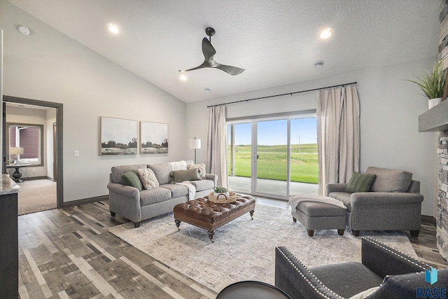 living room featuring wood-type flooring, high vaulted ceiling, a textured ceiling, ceiling fan, and a fireplace