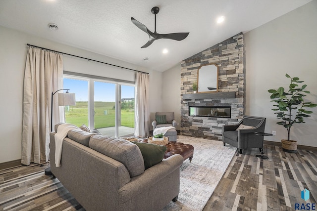 living room with a fireplace, dark wood-type flooring, vaulted ceiling, and ceiling fan