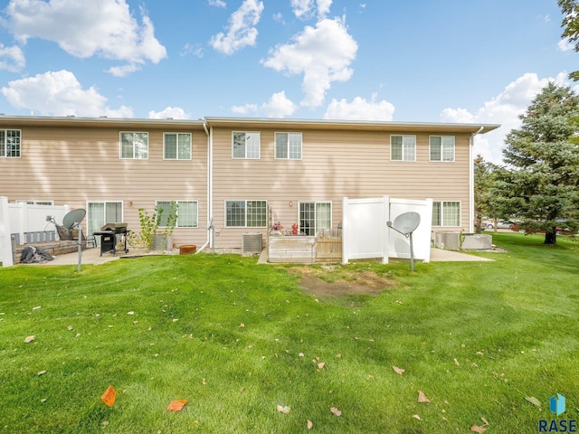 back of property with central AC, a lawn, and a patio area