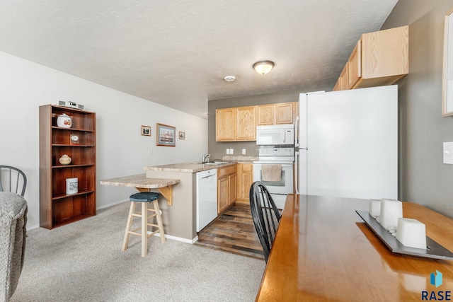 kitchen with white appliances, a kitchen breakfast bar, dark carpet, and light brown cabinets