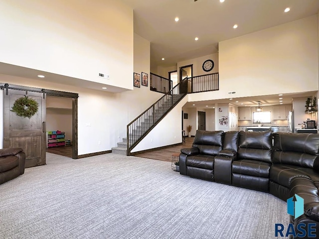 living room with carpet flooring, a barn door, and a high ceiling