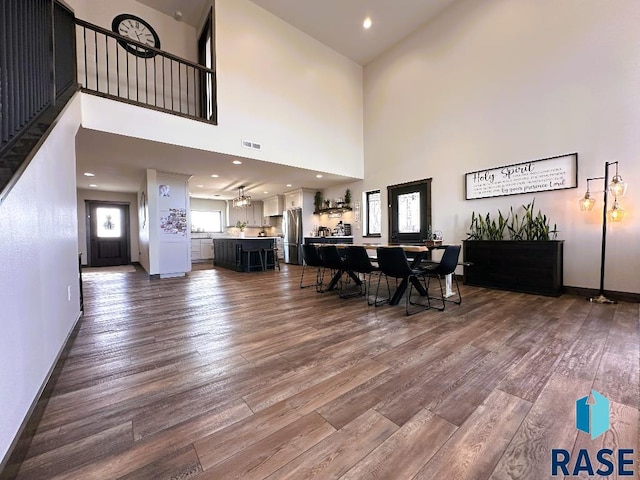 unfurnished dining area featuring a towering ceiling, hardwood / wood-style floors, and ceiling fan