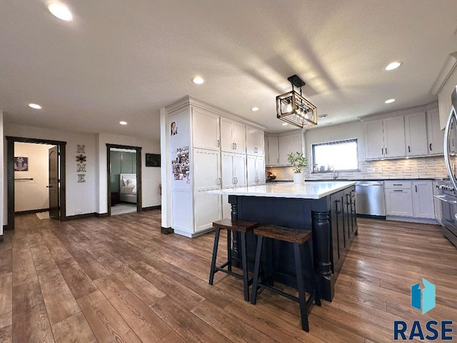 kitchen with hanging light fixtures, dark wood-type flooring, a center island, and dishwasher