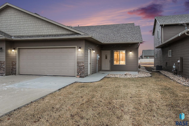 view of front of home featuring cooling unit, a garage, and a yard