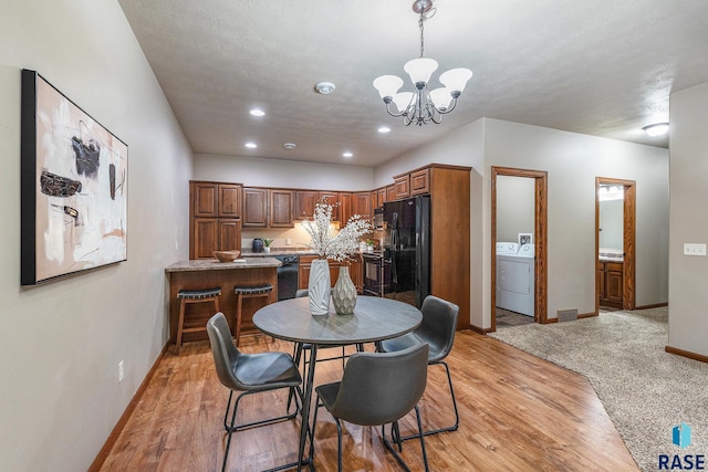 dining room with an inviting chandelier, washer / dryer, and light hardwood / wood-style floors