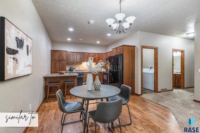 dining area with an inviting chandelier, washer / dryer, and light wood-type flooring