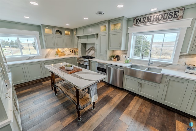 kitchen featuring dark wood-type flooring, stainless steel appliances, green cabinets, and decorative backsplash