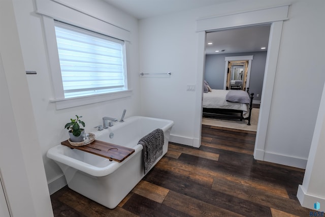 bathroom with hardwood / wood-style flooring and a tub to relax in