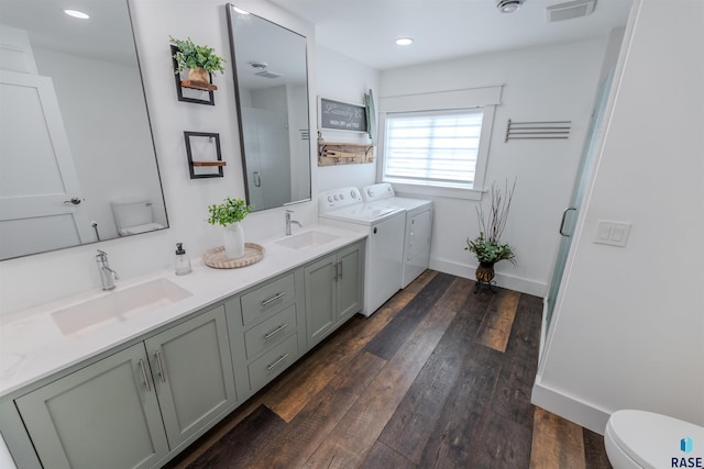 bathroom with hardwood / wood-style floors, a shower with shower door, vanity, washing machine and clothes dryer, and toilet