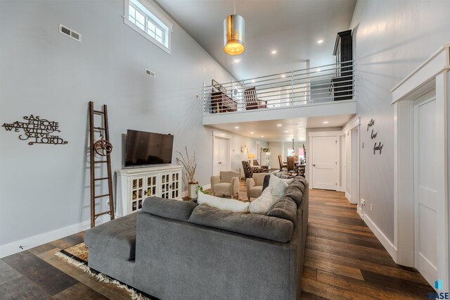 living room featuring a towering ceiling and dark hardwood / wood-style flooring