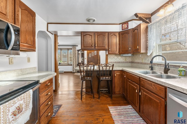 kitchen with tasteful backsplash, appliances with stainless steel finishes, sink, and dark wood-type flooring