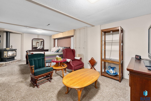 sitting room featuring light colored carpet, a textured ceiling, and a wood stove