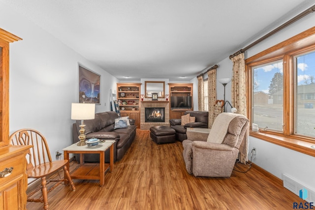 living room with a brick fireplace and hardwood / wood-style floors