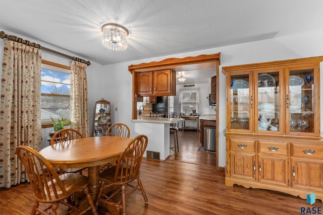 dining space with dark hardwood / wood-style flooring, a chandelier, sink, and a textured ceiling