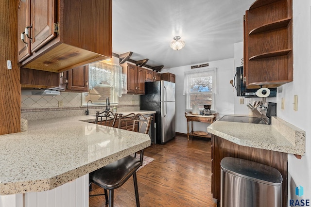 kitchen with a breakfast bar area, kitchen peninsula, and stainless steel refrigerator