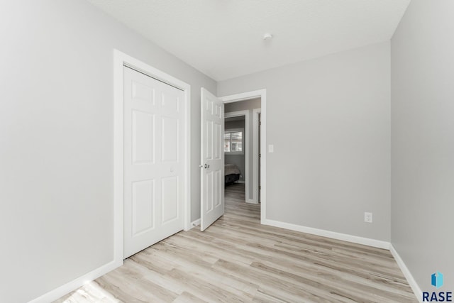 unfurnished bedroom with a textured ceiling, a closet, and light wood-type flooring