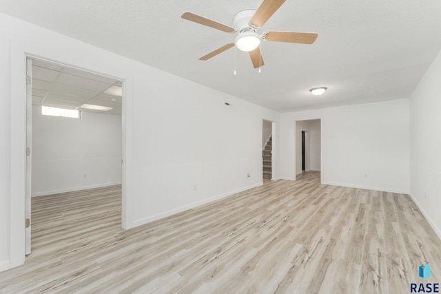 unfurnished room featuring a paneled ceiling, ceiling fan, and light wood-type flooring