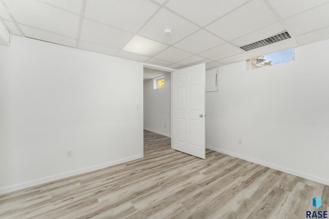 basement featuring a wealth of natural light, a drop ceiling, and light hardwood / wood-style floors