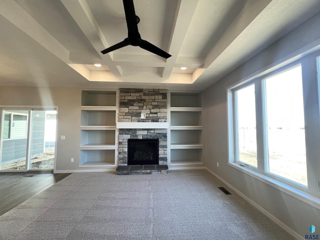 unfurnished living room with a fireplace, baseboards, coffered ceiling, and built in features