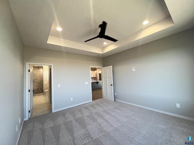 unfurnished bedroom with carpet, a raised ceiling, baseboards, and recessed lighting