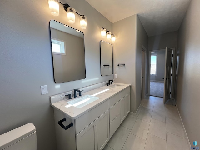 bathroom featuring double vanity, a sink, toilet, and baseboards