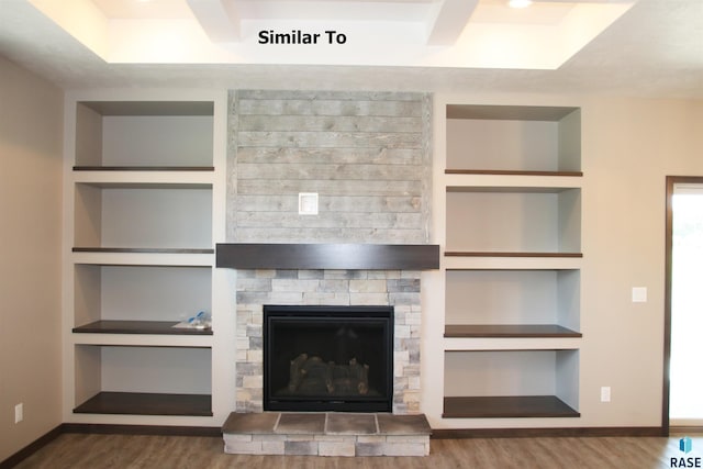 unfurnished living room featuring baseboards, built in features, dark wood-style flooring, and a stone fireplace