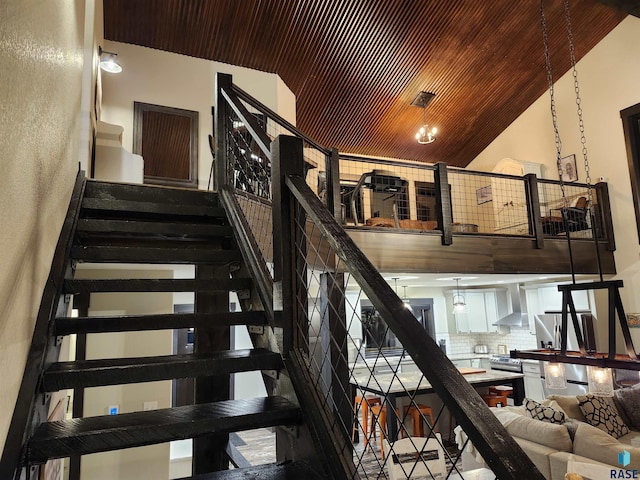 stairway featuring a towering ceiling and wood ceiling