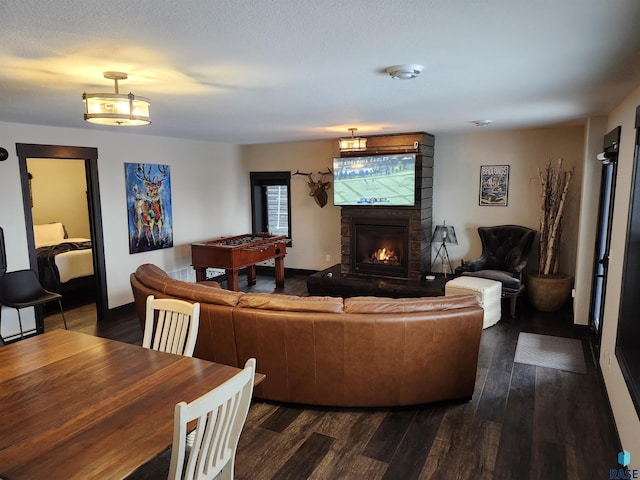 living room featuring a stone fireplace and dark hardwood / wood-style flooring