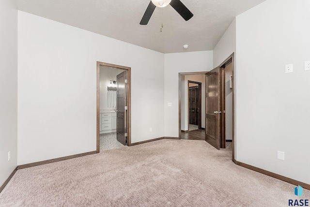 unfurnished bedroom with ceiling fan, ensuite bathroom, and light colored carpet