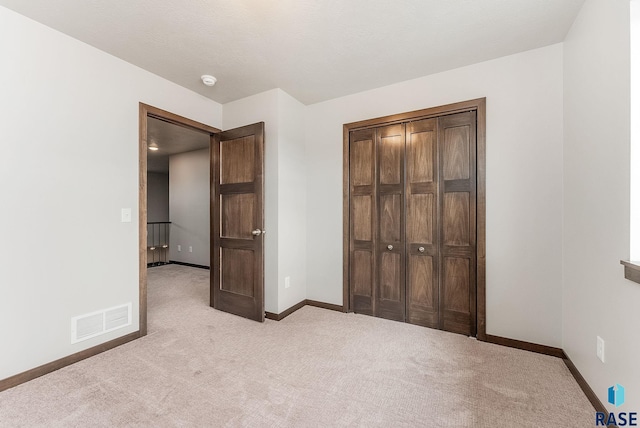 unfurnished bedroom with light carpet and a closet