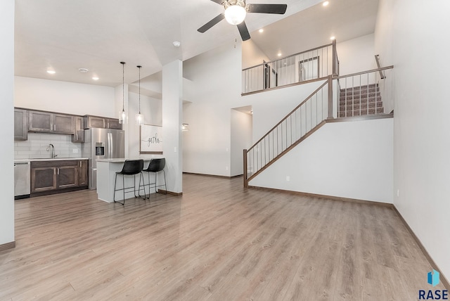 living room featuring ceiling fan, sink, light hardwood / wood-style floors, and high vaulted ceiling