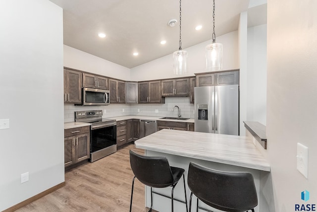 kitchen featuring pendant lighting, backsplash, stainless steel appliances, and dark brown cabinetry