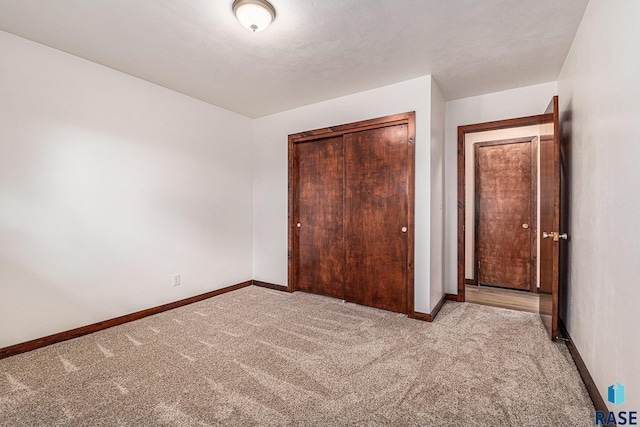 unfurnished bedroom with light colored carpet and a closet