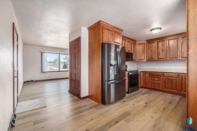 kitchen featuring appliances with stainless steel finishes, light hardwood / wood-style flooring, and a textured ceiling